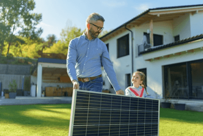 Man and his daughter holding a solar panel